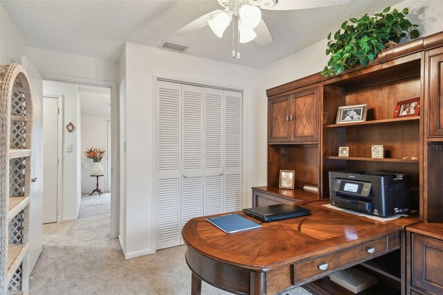 office area with a textured ceiling, ceiling fan, and light colored carpet