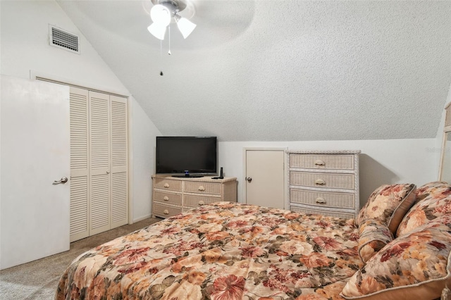 bedroom with a closet, vaulted ceiling, light colored carpet, a textured ceiling, and ceiling fan