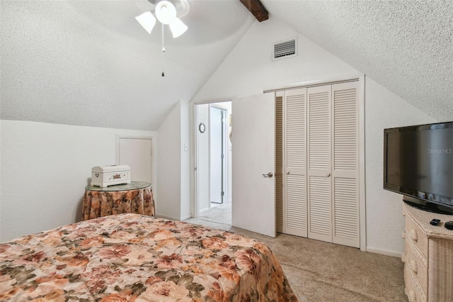 bedroom featuring a closet, ceiling fan, light carpet, lofted ceiling with beams, and a textured ceiling