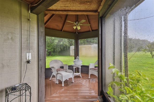 sunroom / solarium featuring beam ceiling and ceiling fan