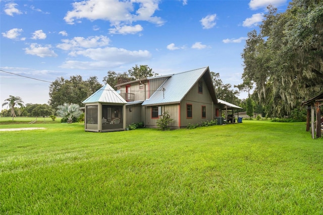 rear view of property featuring a yard and a sunroom