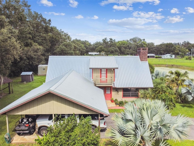 back of property featuring a balcony and a lawn