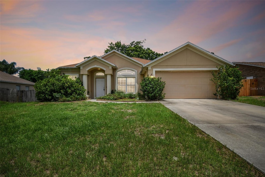 single story home with a garage and a lawn