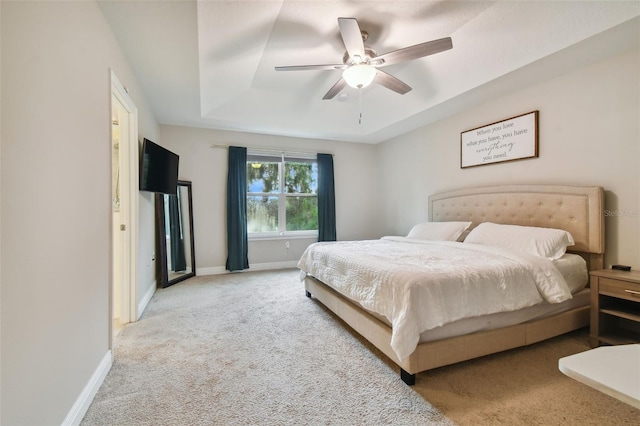 carpeted bedroom featuring ceiling fan and a tray ceiling