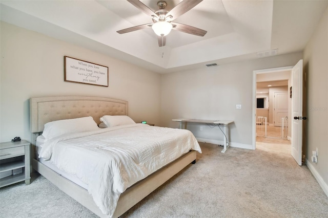 bedroom featuring light carpet, ceiling fan, and a raised ceiling