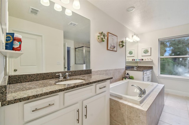 bathroom with a relaxing tiled tub, tile patterned flooring, and double vanity