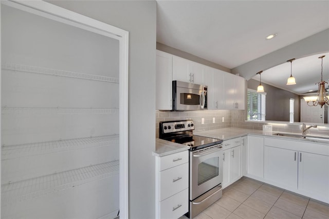 kitchen featuring appliances with stainless steel finishes, white cabinetry, sink, backsplash, and hanging light fixtures