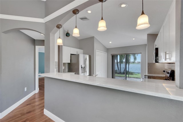 kitchen with white cabinetry, stainless steel appliances, hanging light fixtures, and backsplash