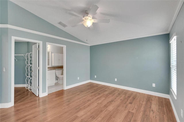 unfurnished bedroom with lofted ceiling, ensuite bathroom, a walk in closet, a closet, and ceiling fan