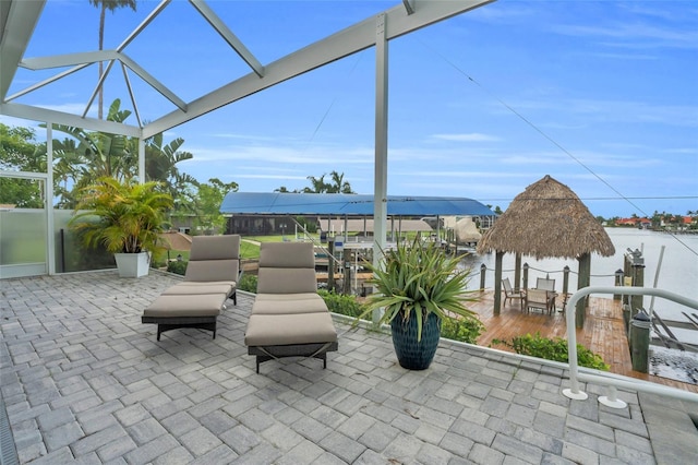 view of patio / terrace featuring a water view and glass enclosure