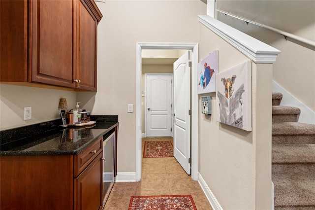 kitchen with beverage cooler, dark stone countertops, and light tile patterned floors