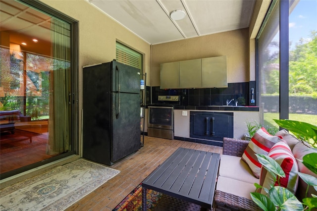 interior space featuring backsplash, fridge, a healthy amount of sunlight, and stove