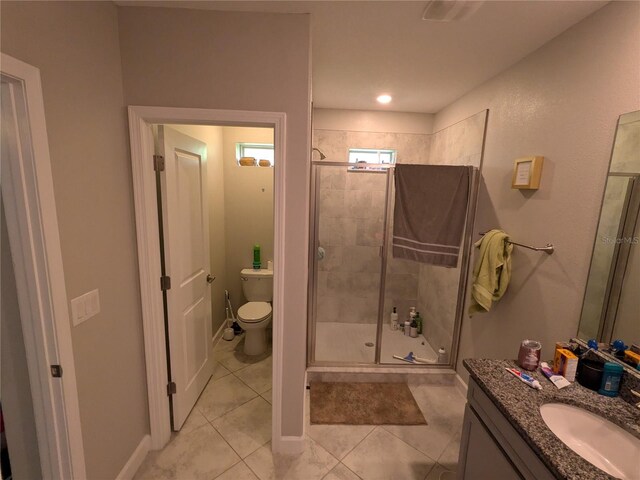 bathroom featuring vanity, toilet, a shower with shower door, and tile patterned floors