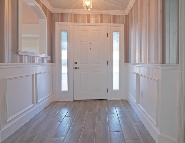 foyer entrance featuring wood-type flooring, crown molding, and a textured ceiling