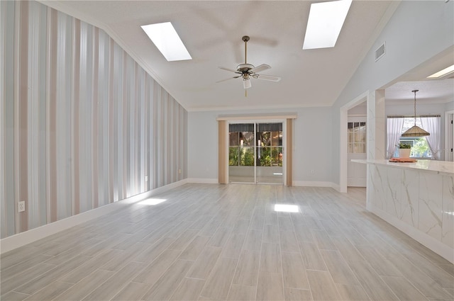 unfurnished living room featuring lofted ceiling with skylight, ornamental molding, and a wealth of natural light