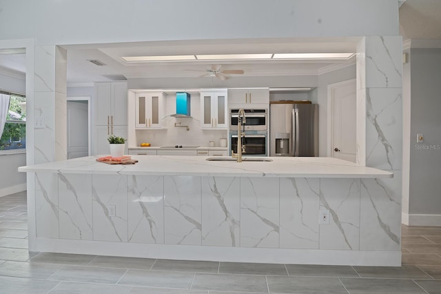 kitchen featuring stainless steel appliances, sink, light tile patterned floors, white cabinetry, and wall chimney exhaust hood