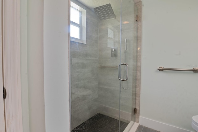 bathroom featuring a shower with door and toilet