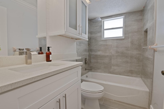 full bathroom with vanity, tiled shower / bath combo, toilet, a textured ceiling, and tile patterned flooring