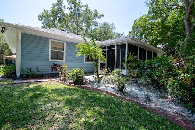 rear view of property featuring cooling unit, a sunroom, and a yard