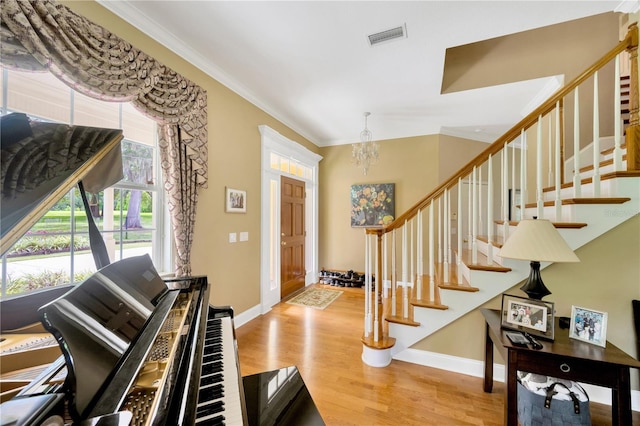 foyer entrance featuring ornamental molding, a notable chandelier, and light wood-type flooring