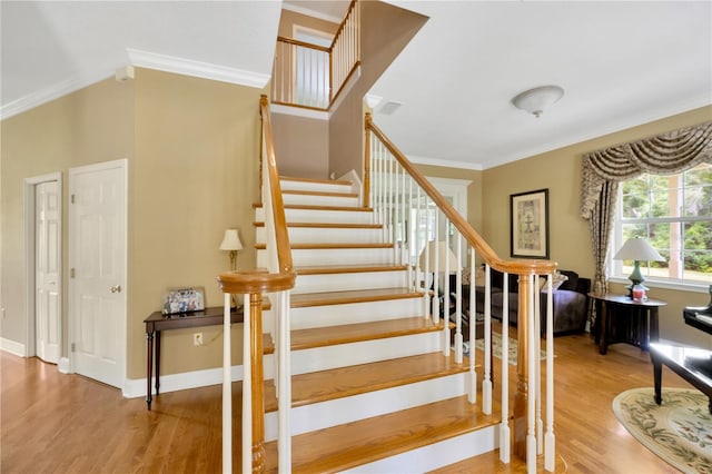 stairs with hardwood / wood-style flooring and ornamental molding