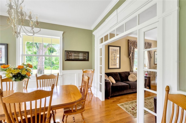 dining area with french doors, ornamental molding, light hardwood / wood-style floors, and a notable chandelier