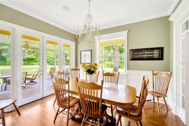 dining space with crown molding, a chandelier, french doors, and light wood-type flooring