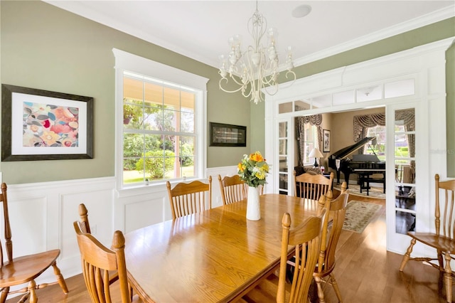 dining room featuring wood-type flooring, ornamental molding, french doors, and a chandelier