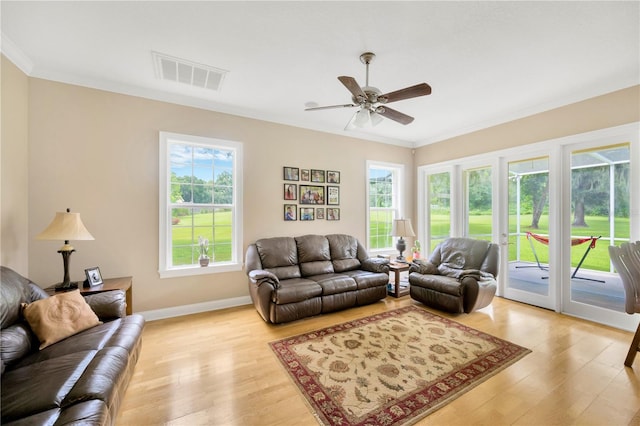 living room with crown molding, plenty of natural light, and light hardwood / wood-style flooring