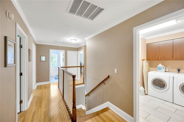 laundry room featuring crown molding, cabinets, washer and dryer, and light hardwood / wood-style flooring