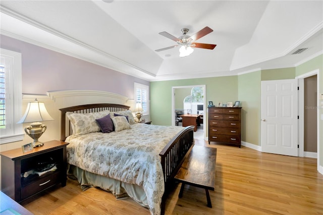 bedroom with crown molding, ceiling fan, a tray ceiling, and light hardwood / wood-style floors