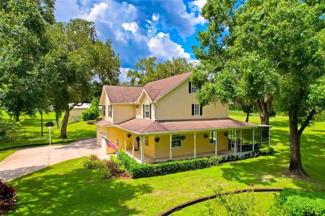 view of side of home with a garage, a sunroom, a porch, and a lawn