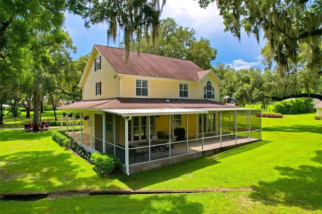 rear view of house featuring a lawn, a sunroom, and a patio area