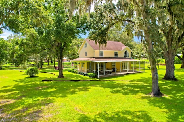 rear view of house featuring a sunroom and a lawn