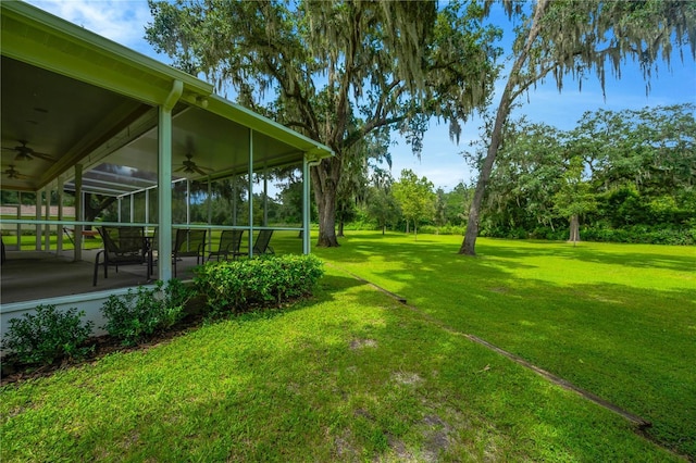 view of yard with ceiling fan, a sunroom, and glass enclosure