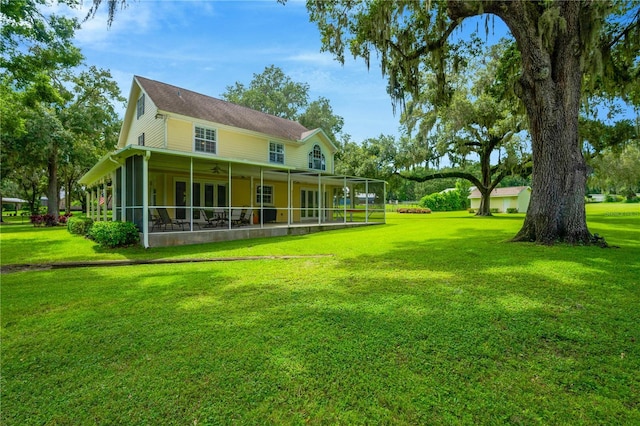 rear view of property featuring ceiling fan and a lawn