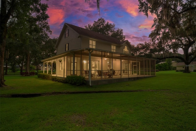 back house at dusk featuring a yard and a patio