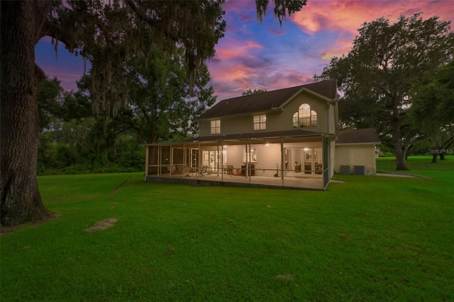 back house at dusk featuring a sunroom, a yard, and a patio area