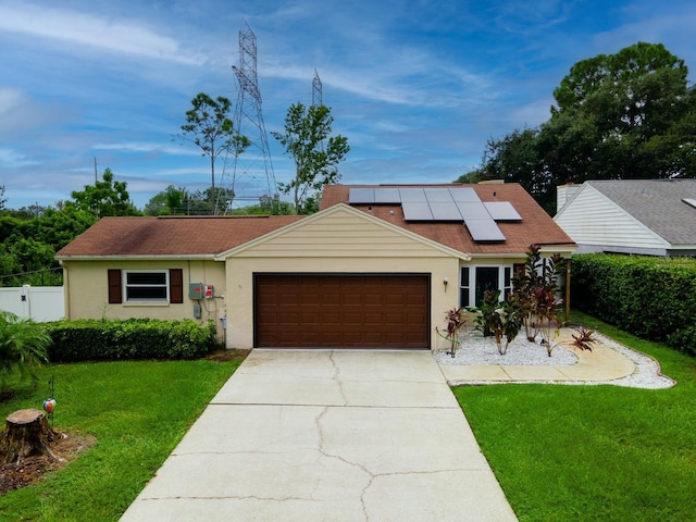 single story home featuring a garage, solar panels, and a front lawn