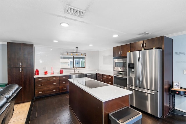 kitchen with appliances with stainless steel finishes, decorative light fixtures, sink, a center island, and crown molding