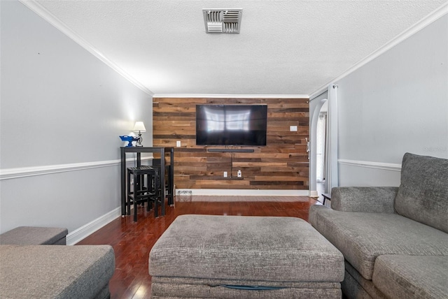 living room featuring crown molding, wooden walls, dark hardwood / wood-style floors, and a textured ceiling