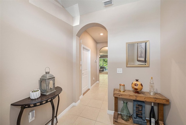 hallway with a textured ceiling and light tile patterned floors