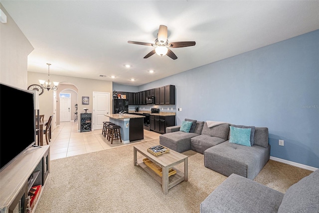 tiled living room featuring ceiling fan with notable chandelier