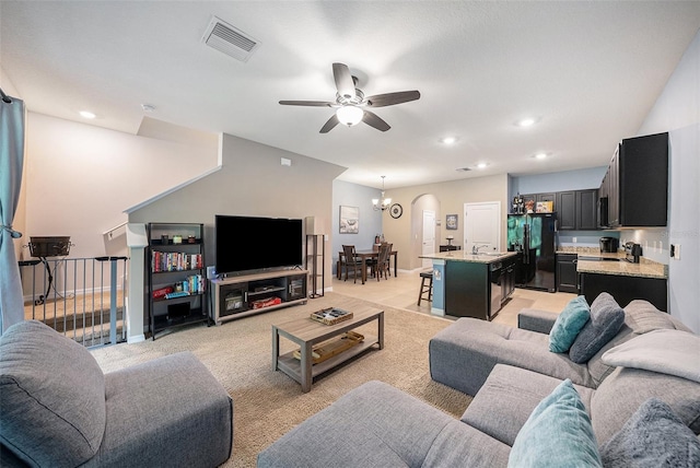 living room with sink, ceiling fan with notable chandelier, and light colored carpet