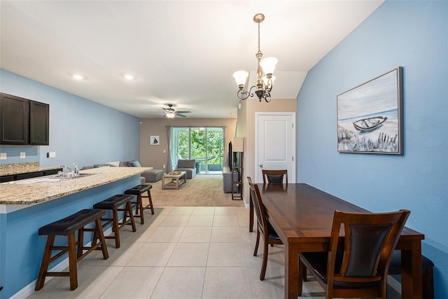 tiled dining space with sink and ceiling fan with notable chandelier