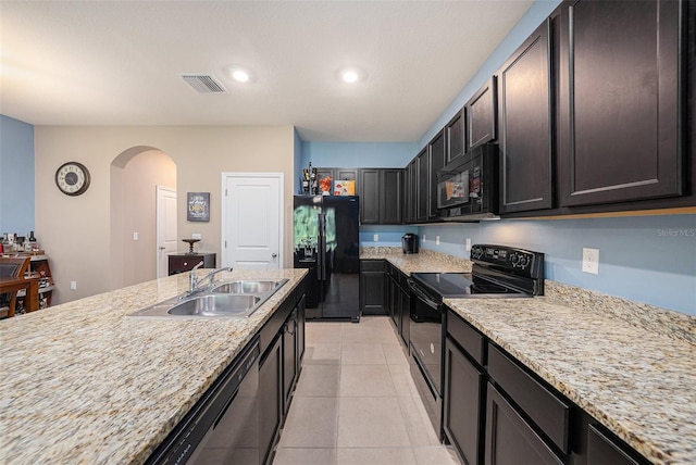 kitchen featuring black appliances, light tile patterned floors, dark brown cabinets, sink, and light stone counters