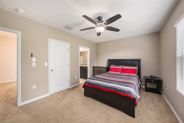 bedroom with light carpet, ensuite bath, and ceiling fan