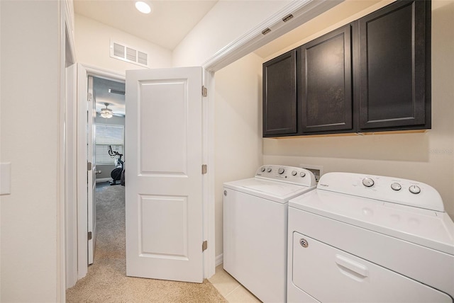 clothes washing area featuring light carpet, washing machine and clothes dryer, and cabinets