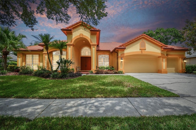 mediterranean / spanish-style home featuring a garage and a lawn