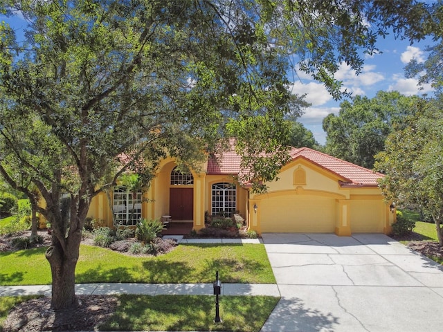 mediterranean / spanish home featuring a garage and a front lawn